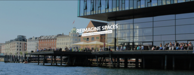 Gebäude mit großer Terrasse voller Menschen, am Wasser